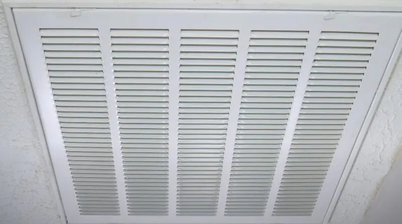 A clean, white ceiling vent, showcasing a precise grid pattern