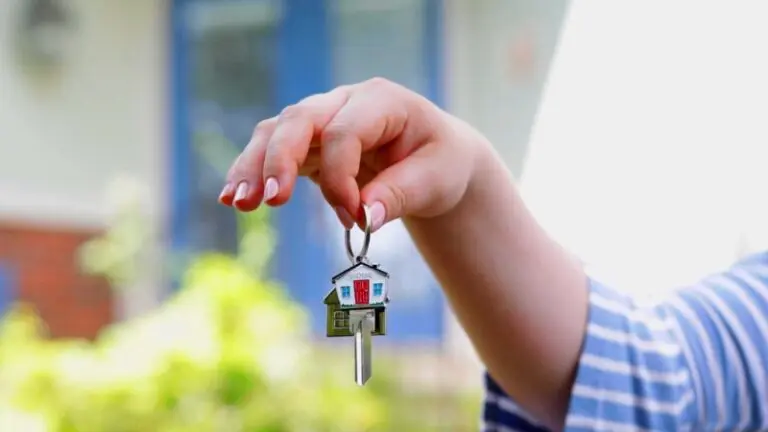 A Tenant in Indiana holds a house-shaped keychain while standing outside a rental home