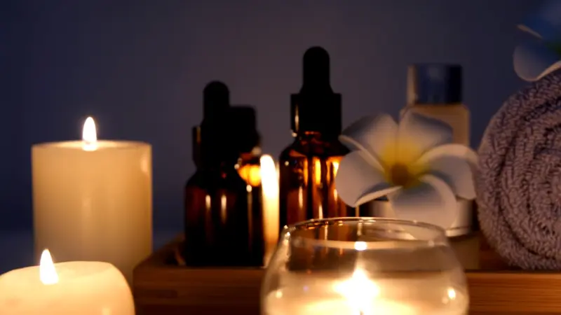 Soft candlelight reflects off oils and towels arranged for a calm visit to spa centers