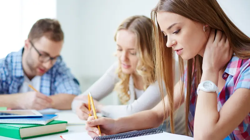 Students focus on writing admissions essays during a study session as application expectations tighten